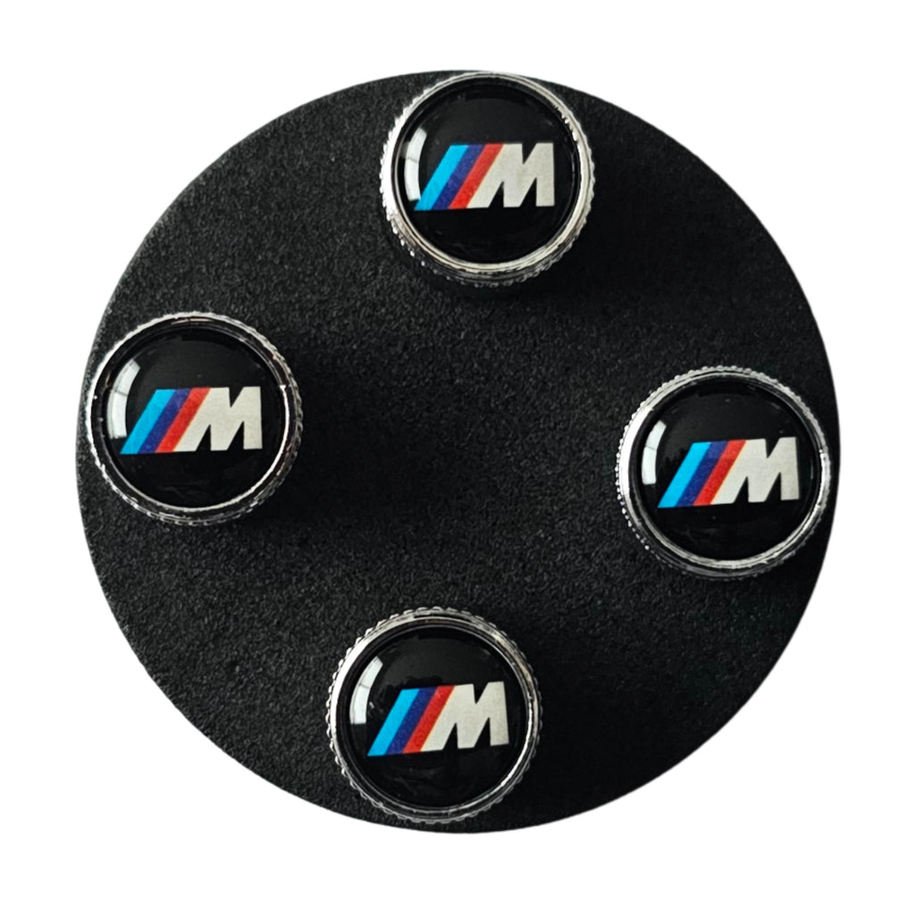 BMW tyre valve stem caps on a black foam display circle