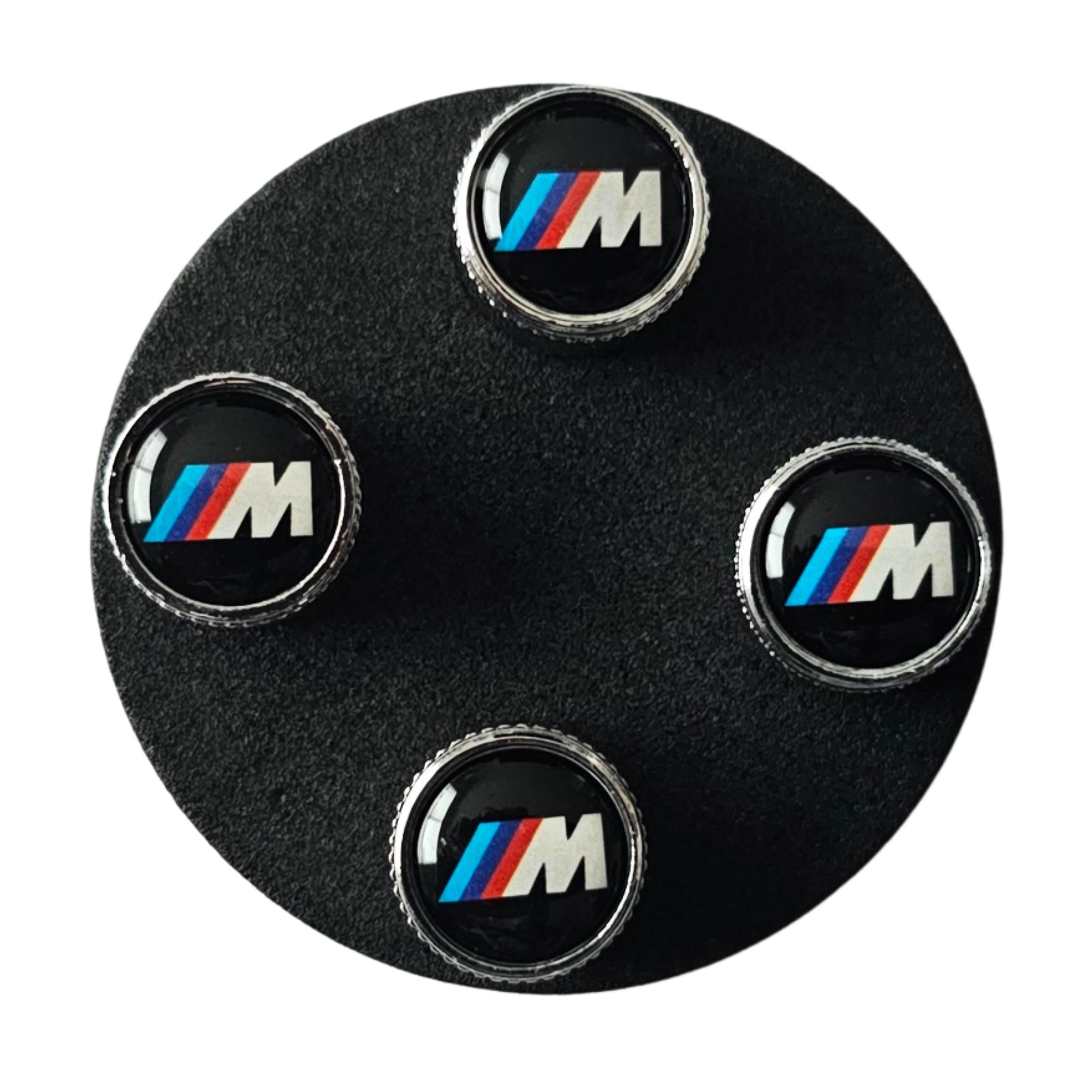 BMW tyre valve stem caps on a black foam display circle