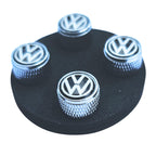 Set of VW Volkswagen logo metal tire valve caps on a black circular base