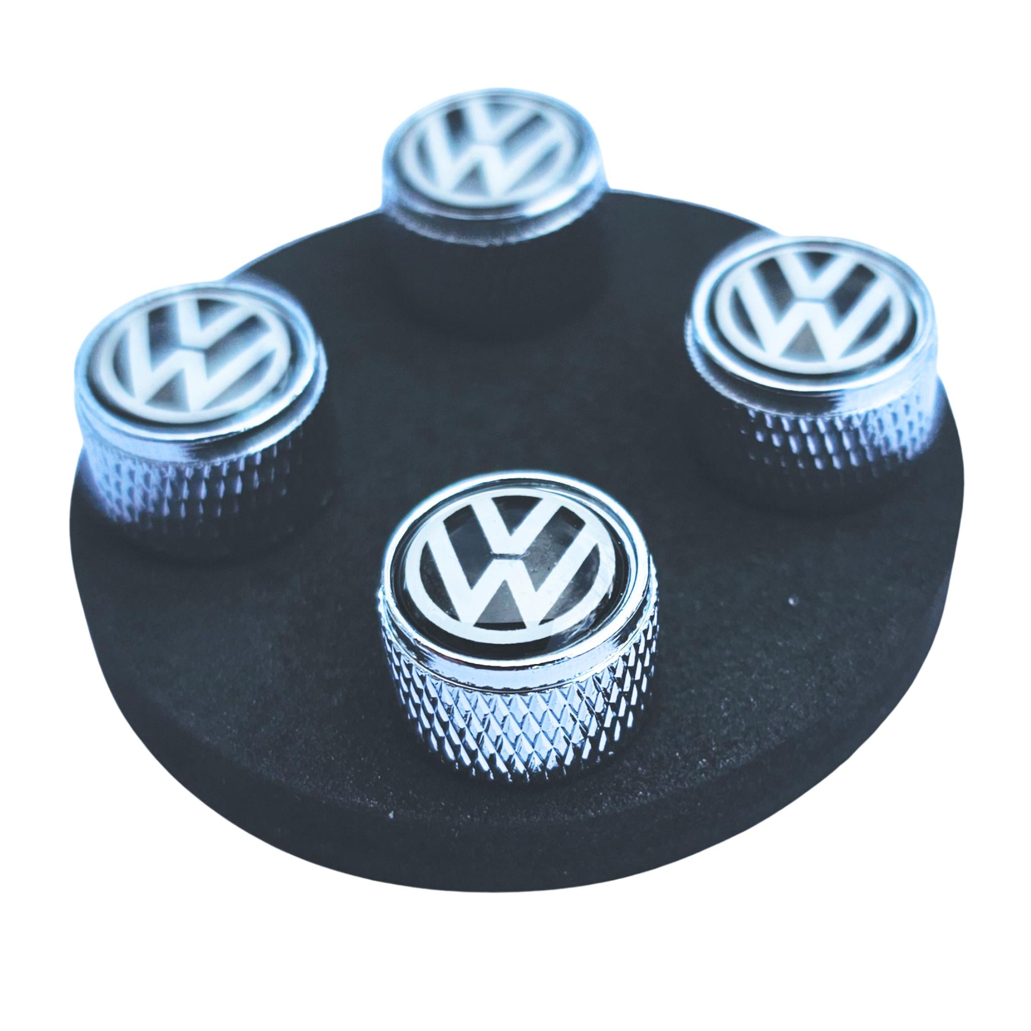 Set of VW Volkswagen logo metal tire valve caps on a black circular base