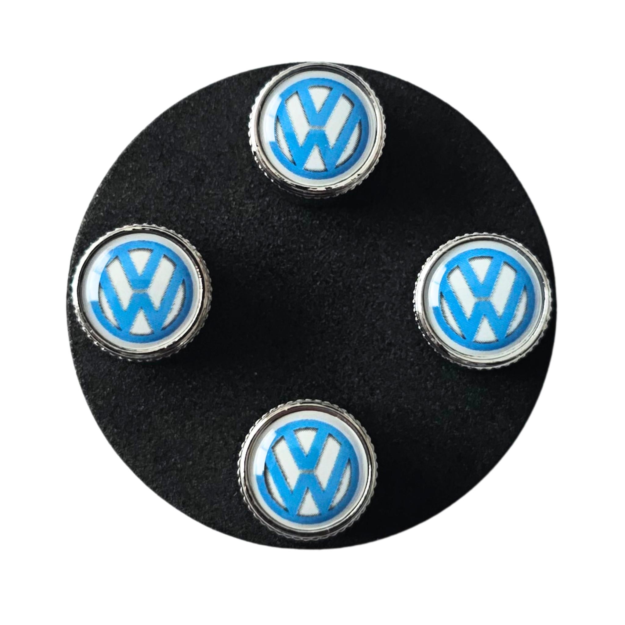 Four VW Volkswagen logo tyre valve caps on a black background