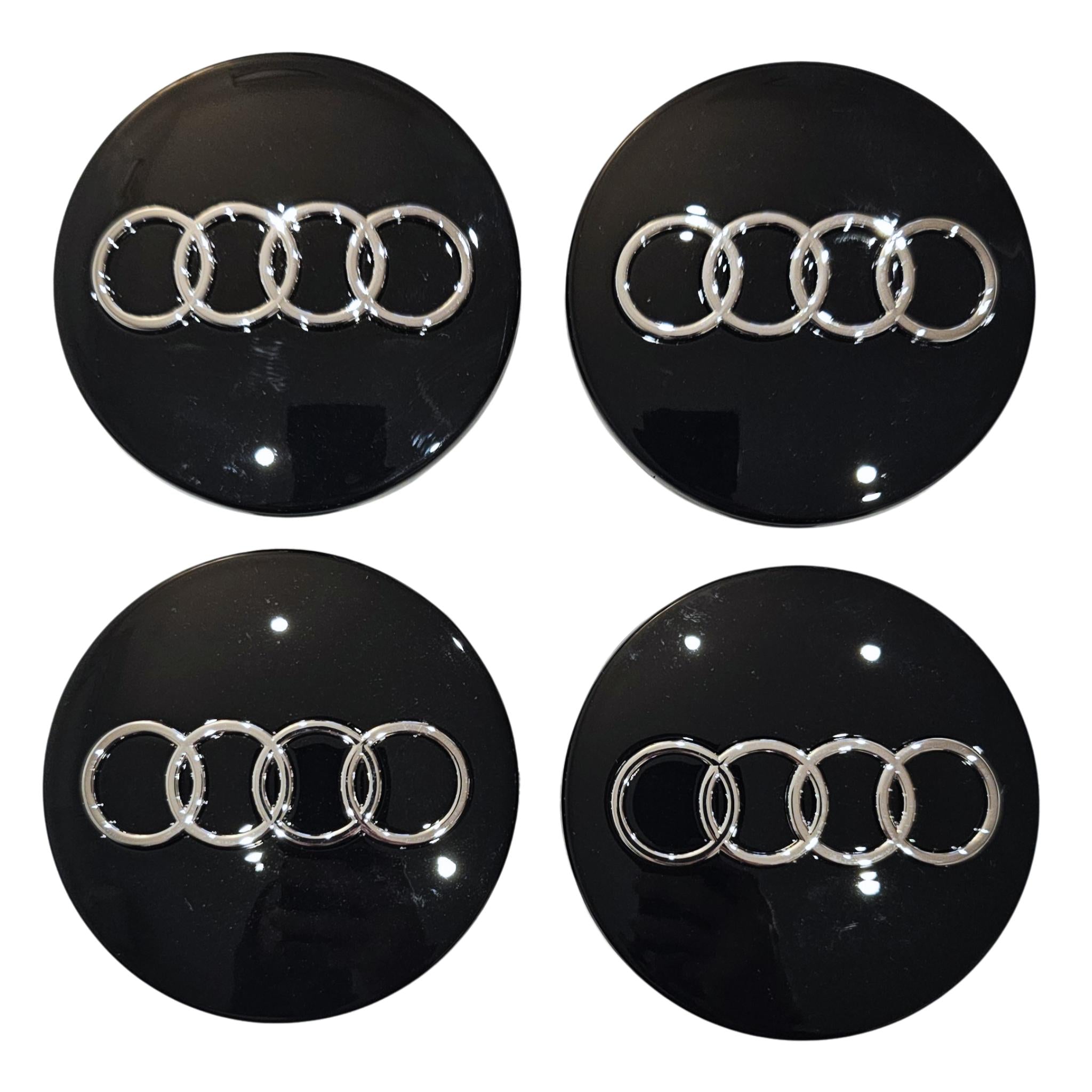 Four black Audi 68mm wheel centre caps with silver Audi logo on a white background