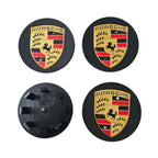 Four 65mm porsche wheel centre caps in black one face down  on white background